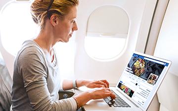 一名女乘客在她的笔记本电脑上使用飞机互联网浏览Facebook