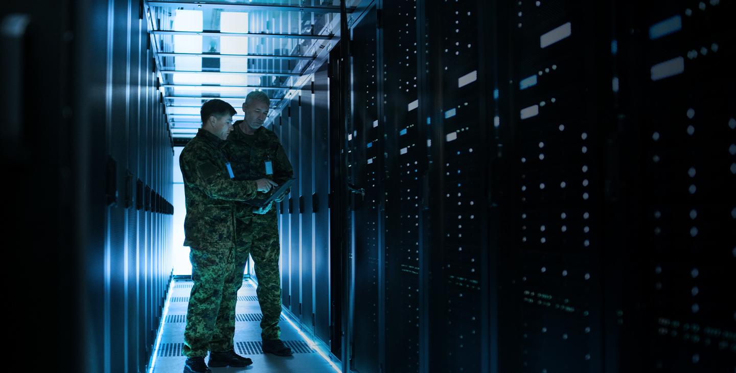 两名身穿军装的男子在服务器室用平板电脑讨论政府的网络安全问题