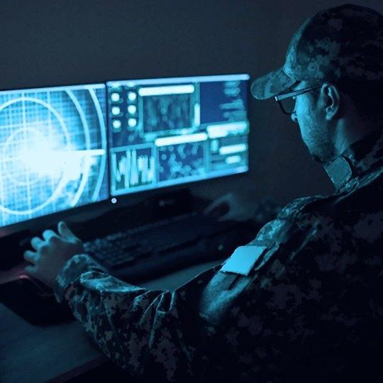 身穿绿色军装的男子坐在一台由政府网络安全系统保护的电脑前