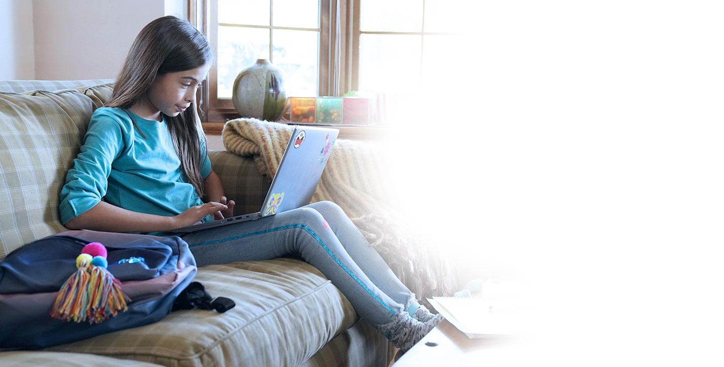 一名年轻的女学生对通过sat的网络安全软件感到很安全, 在沙发上用笔记本电脑做作业
